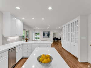 Kitchen featuring light wood-style floors, a peninsula, white cabinets, decorative backsplash, and recessed lighting