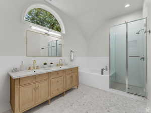 Bathroom with a shower stall, double vanity, a bath, light floors, and a wainscoted wall