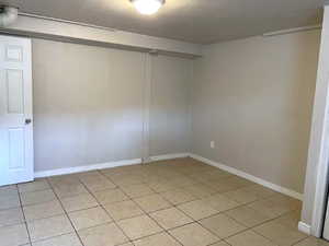 Unfurnished room with a textured ceiling and light tile patterned floors