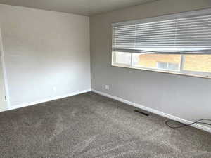 Unfurnished room with a textured wall and dark colored carpet