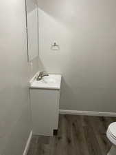 Half bathroom with vanity and dark wood-style floors