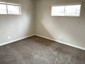 Empty room with a textured wall, plenty of natural light, and carpet floors