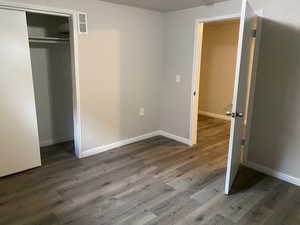 Unfurnished bedroom featuring dark wood-type flooring and a closet