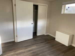 Unfurnished bedroom featuring dark wood-style floors and a closet