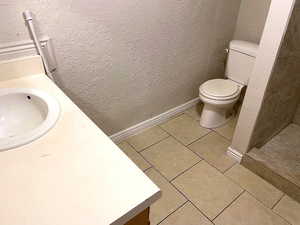 Bathroom with vanity, light tile patterned floors, and a textured wall
