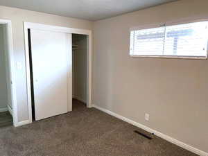 Unfurnished bedroom featuring carpet, a textured wall, a closet, and a textured ceiling