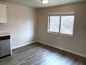Unfurnished dining area featuring dark wood finished floors and a textured ceiling