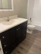 Bathroom featuring vanity, dark wood-style floors, and shower / bathtub combination