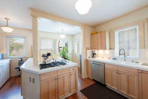 Kitchen with light brown cabinets, dark wood-style floors, tile countertops, appliances with stainless steel finishes, and ornamental molding