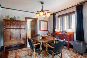 Dining room with light wood-style flooring, ornamental molding, and a chandelier