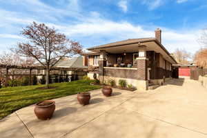 View of side of property featuring a chimney, stucco siding, a patio, and brick siding