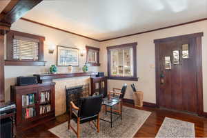 Dining room with a fireplace, dark wood-style flooring, crown molding, and healthy amount of natural light