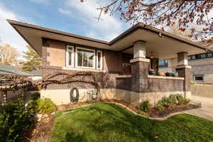 View of side of home featuring brick siding, stucco siding, and a lawn