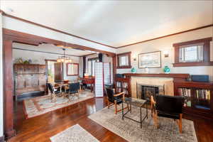 Living area with ornamental molding, dark wood-style flooring, a fireplace, and a chandelier