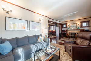Living room featuring crown molding, wood finished floors, and a fireplace
