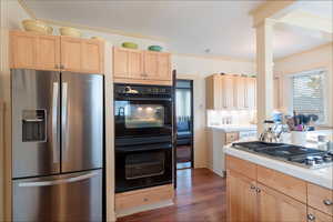Kitchen featuring light brown cabinets, stainless steel appliances, tile countertops, crown molding, and dark wood-type flooring