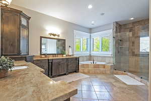Primary bath with two vanities, a large walk-in shower, a garden tub, travertine floors and recessed lighting