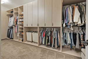 Primary Walk in closet with light colored carpet