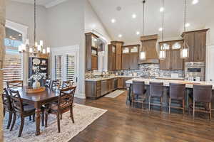 Dining space featuring high vaulted ceiling, a chandelier, dark wood-style floors, lots of natural light, and recessed lighting