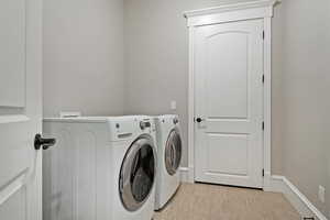 Laundry area featuring washing machine and clothes dryer and light wood-style flooring