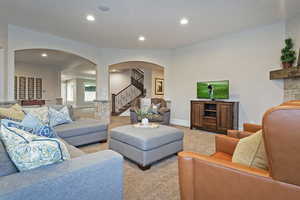 Living area featuring arched walkways, stairway, carpet, and recessed lighting