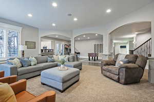 Living room with stairs, arched walkways, and recessed lighting