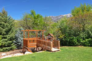 View of grassy yard featuring a deck with mountain view and a playground