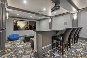 Home theater room with custom carpet floors and crown molding