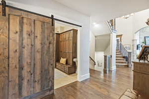 Hallway with a barn door to laundry room, light wood-type flooring, stairs, and arched walkways