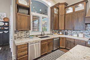 Kitchen with stainless steel dishwasher, light stone countertops, and dark wood-style flooring