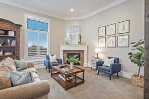 Carpeted living area featuring a brick fireplace, crown molding, and recessed lighting