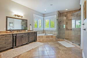Primary Bathroom with vanity, a large walk-in shower, a garden tub, healthy amount of natural light, and recessed lighting