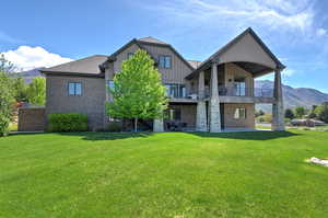 Rear view of house featuring a patio, a mountain view, board and batten siding, and a lawn