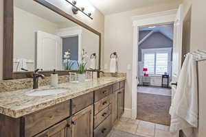 Bathroom with double vanity, vaulted ceiling, and light carpet