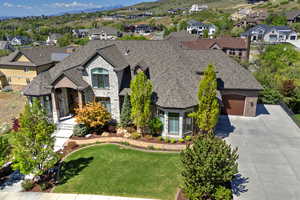 Front of  home featuring stone adn brick siding, a residential view, driveway, a front yard, and a shingled roof