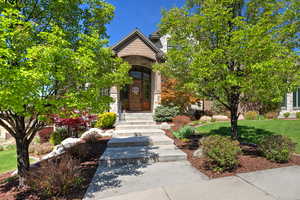 Property entrance with a yard, a chimney, and stone siding