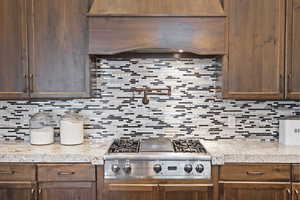 Kitchen featuring custom ventilation hood, stainless steel gas stovetop, and custom cabinetry