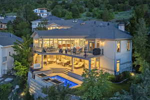 Back of house with an outdoor living space with a fire pit, a balcony, a patio, stone siding, and a chimney