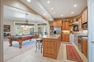 Kitchen featuring billiards table, a kitchen island, hanging light fixtures, arched walkways, and stainless steel appliances