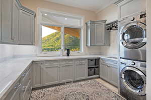 Laundry room with stacked washing machine and dryer, cabinet space, and light tile patterned flooring