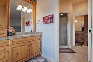 Bathroom featuring vanity, a stall shower, and light tile patterned floors