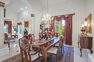 Dining room with ornate columns, a high ceiling, plenty of natural light, a chandelier, and arched walkways