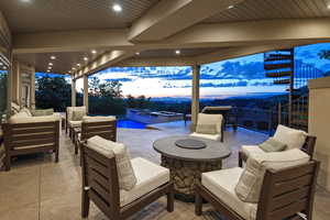 Patio terrace at dusk featuring an outdoor living space with a fire pit, a pool with connected hot tub, a patio area, and stairway
