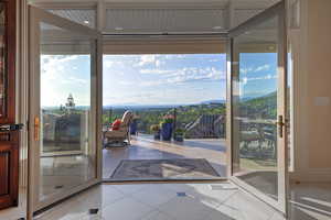 Doorway with a mountain view, tile patterned floors, and floor to ceiling windows