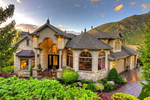 French country style house with stone siding, stucco siding, a garage, and a patio