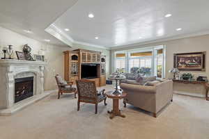 Living room with light carpet, a premium fireplace, recessed lighting, a textured ceiling, and crown molding