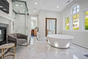 Bathroom with marble tiled floors, a freestanding bath, a marble finish shower, recessed lighting, and a glass covered fireplace