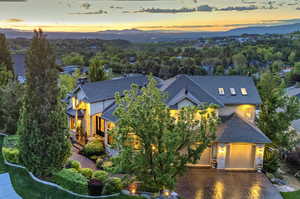 View of front of property featuring a shingled roof, stone siding, a garage, and driveway