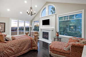 Bedroom with wood finished floors, multiple windows, high vaulted ceiling, a high end fireplace, and access to outside