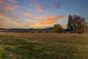 Yard at dusk with a yard, a mountain view, and a view of countryside